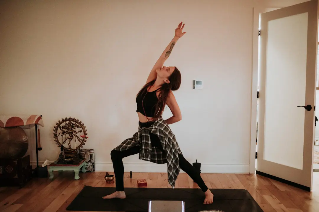 Woman in warrior pose reaching arms overhead
